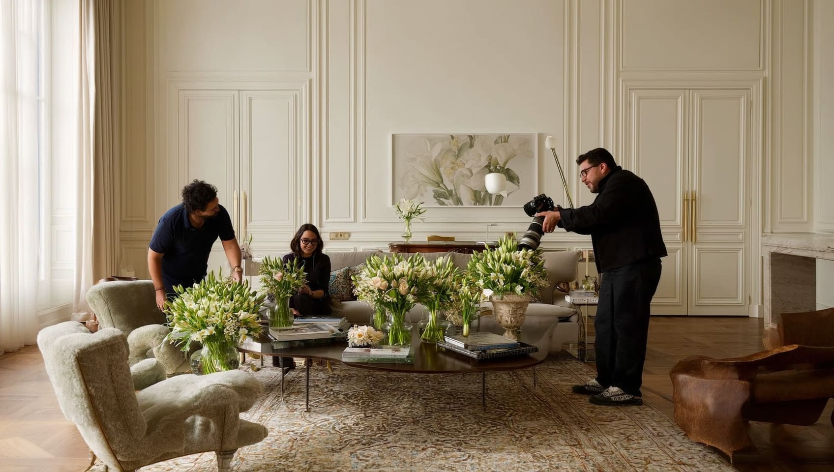 Stylist and photographer composing an editorial shoot in a classic living room filled with fresh flowers